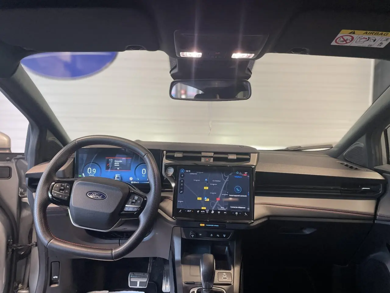 Vue intérieure frontale du tableau de bord du Ford Puma gris clair, avec écran tactile central et volant multifonction.