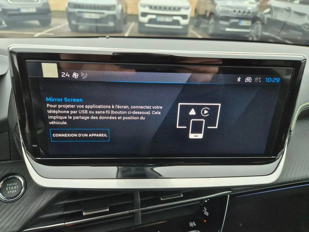 Écran tactile central allumé dans l’habitacle d’une Peugeot 208 gris, vue rapprochée du tableau de bord.