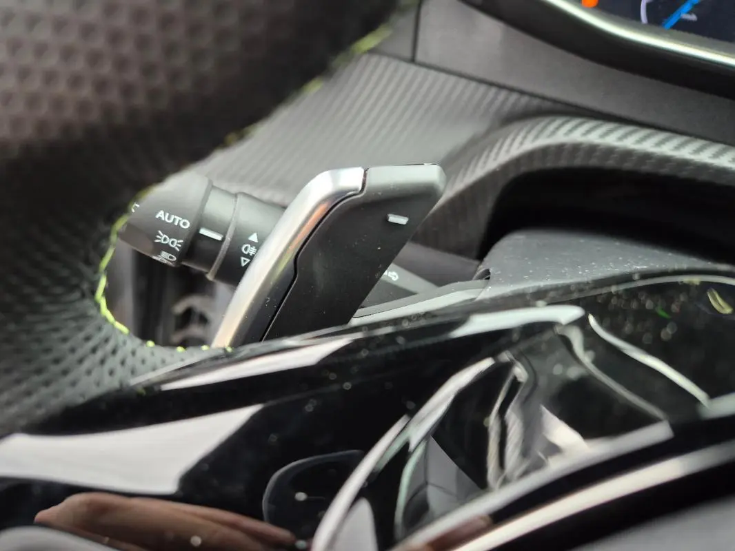 Gros plan sur la palette de changement de vitesse et le commodo d’éclairage dans l’habitacle d’une Peugeot 208 gris 2025.