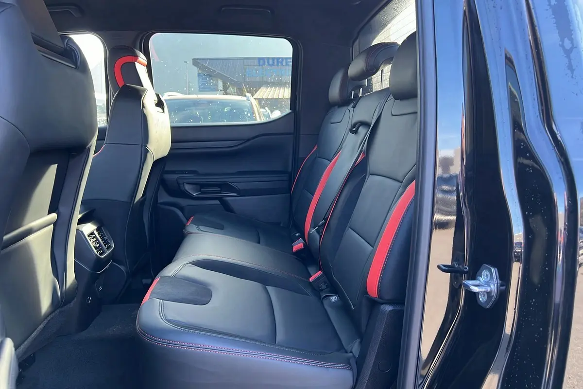 Vue intérieure côté droit sur les sièges arrière noirs avec surpiqûres rouges du Ford Ranger Raptor 2025 noir absolu.