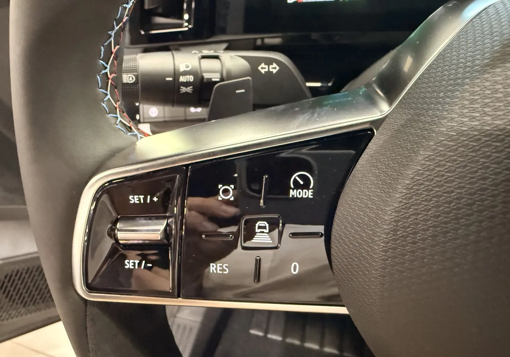 Gros plan sur les commandes au volant du Renault Austral 2026, finition Esprit Alpine avec surpiqûres tricolores.