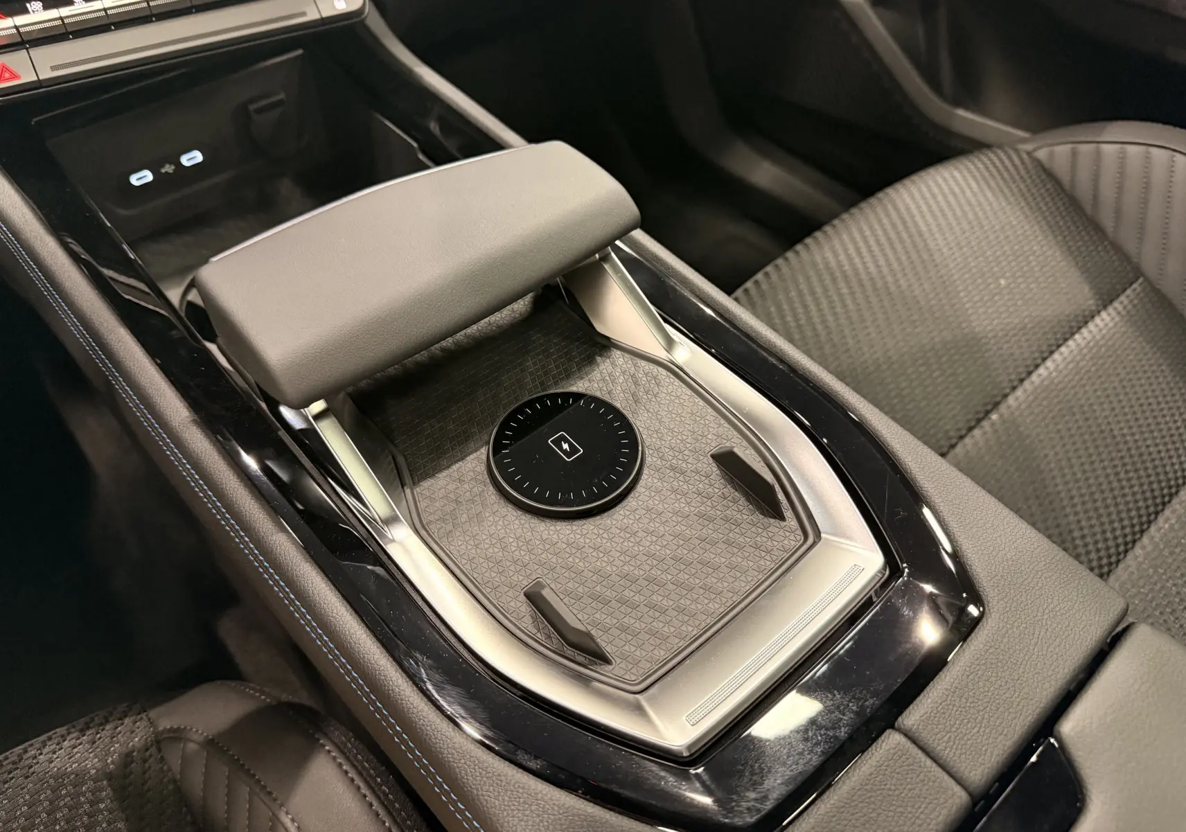 Vue rapprochée de la console centrale du Renault Austral gris avec accoudoir et zone de recharge sans fil.
