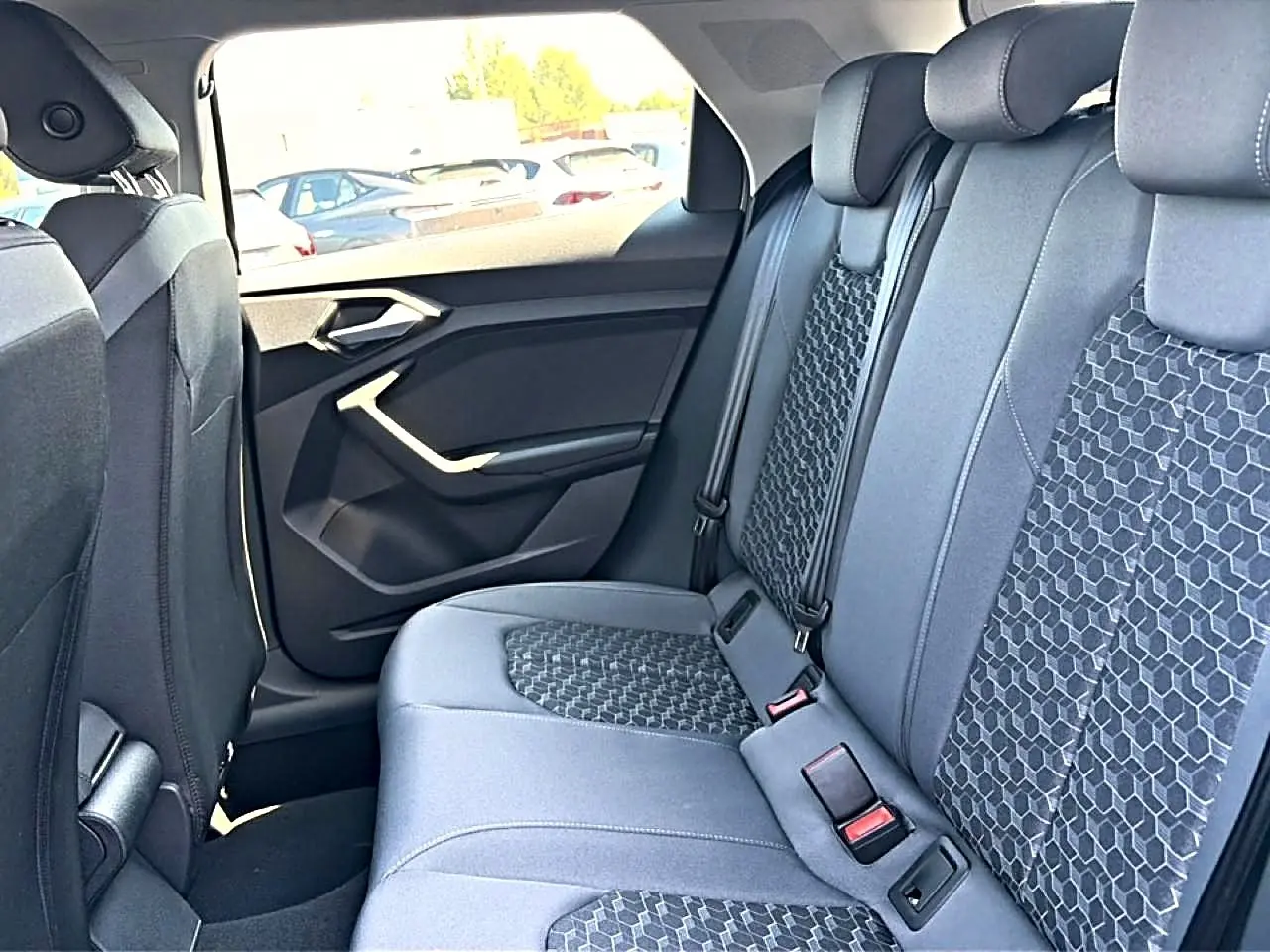 Vue intérieure arrière côté droit de l'Audi A1 Sportback 2026, sièges tissu gris avec motifs hexagonaux.