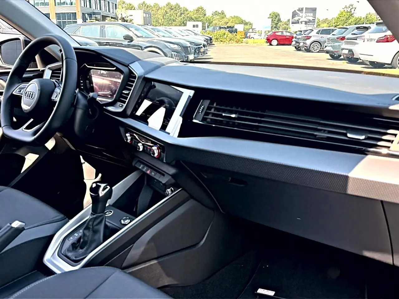 Intérieur noir de l'Audi A1 Sportback 2026 vu côté passager, avec tableau de bord moderne et levier de boîte auto.