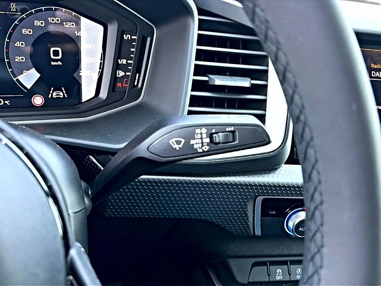 Vue rapprochée du tableau de bord noir de l'Audi A1 Sportback 2026, avec volant et commandes d'essuie-glace visibles.