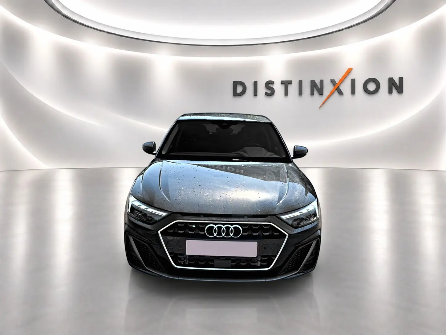 Vue avant d'une Audi A1 Sportback noire 2026 avec calandre hexagonale et phares LED dans un showroom lumineux.