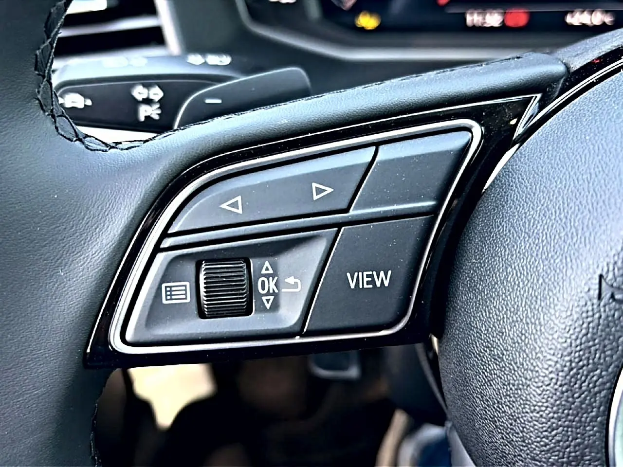 Gros plan sur les commandes gauche du volant cuir noir de l'Audi A1 Sportback 30 TFSI S line 2026.