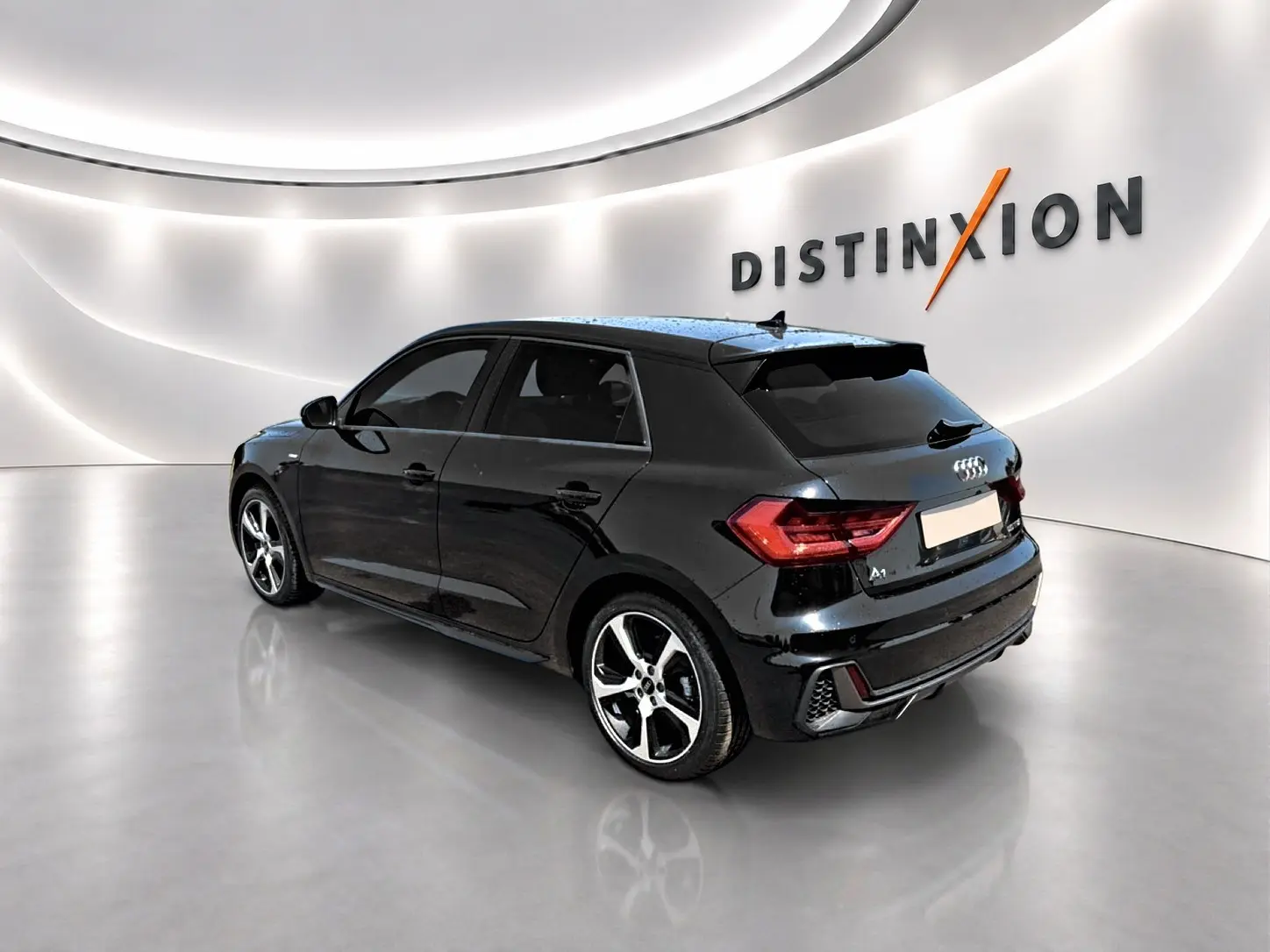 Audi A1 Sportback noir vue 3/4 arrière droit dans un showroom lumineux avec jantes alu distinctives.