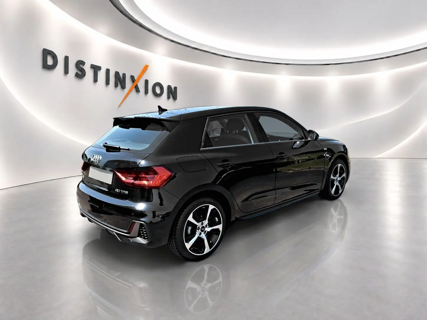 Audi A1 Sportback noir vue 3/4 arrière droit dans un showroom avec jantes alu et becquet arrière.