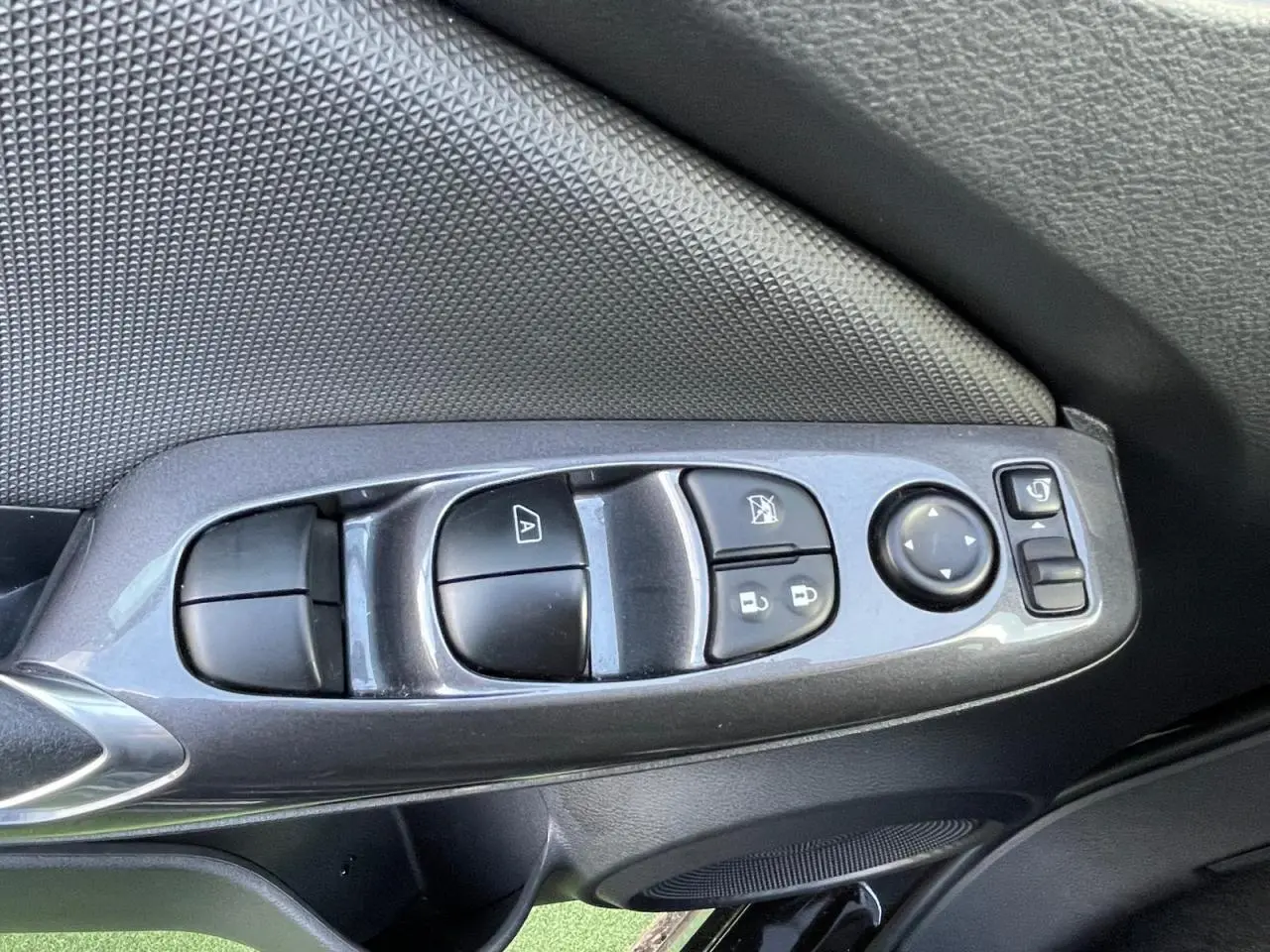 Gros plan sur les commandes des vitres et rétroviseurs côté conducteur du Nissan Juke II gris ceramic 2024.