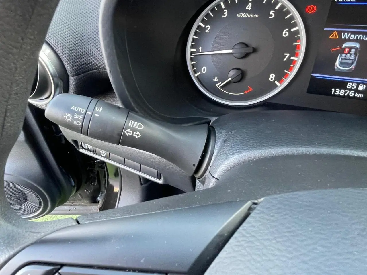 Gros plan sur le combiné d'instruments noir du Nissan Juke 2024 avec compte-tours et levier de clignotants à gauche.