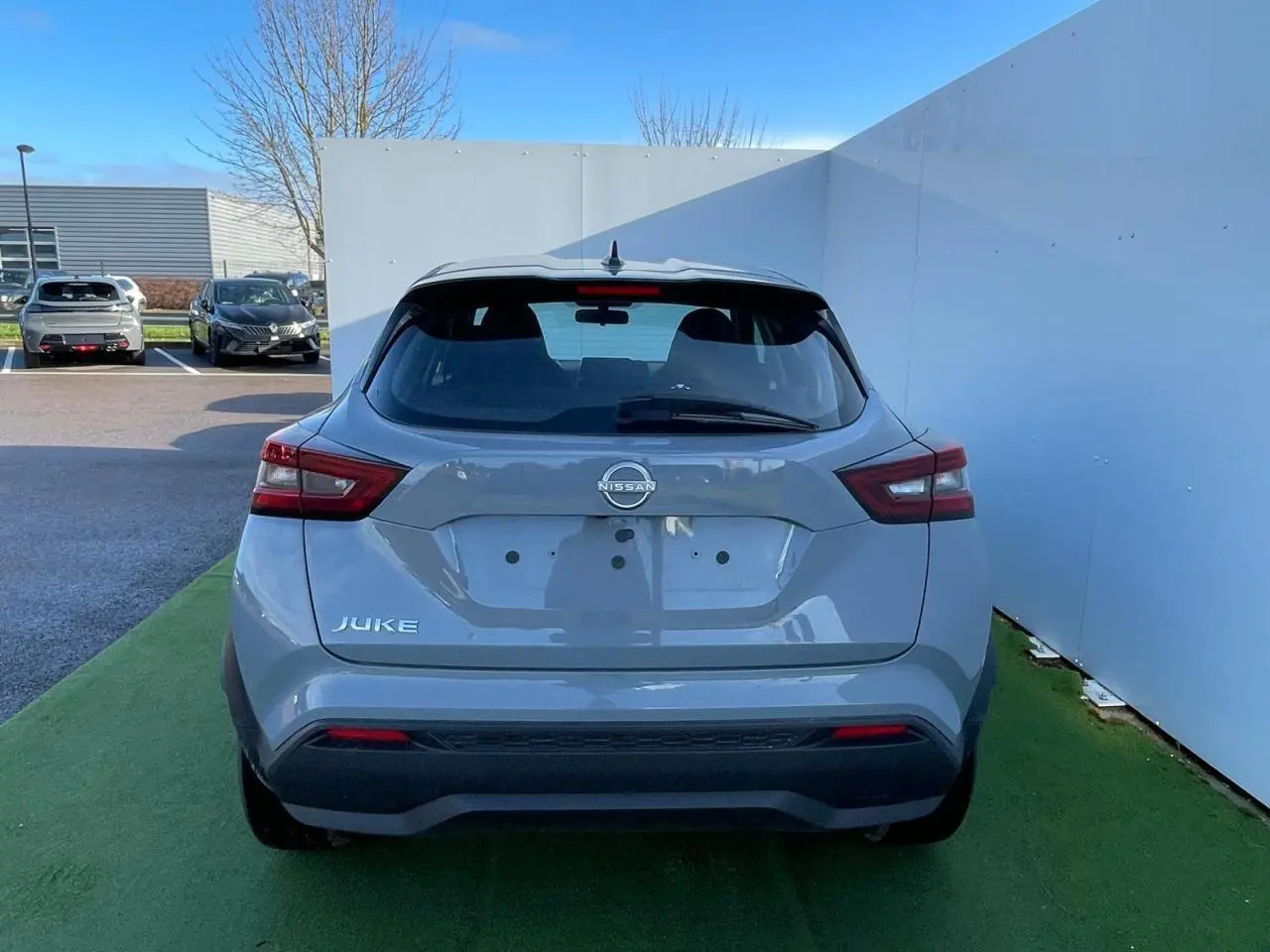 Vue arrière du Nissan Juke II 2024 en gris céramic avec feux arrière LED et antenne aileron de requin noire.