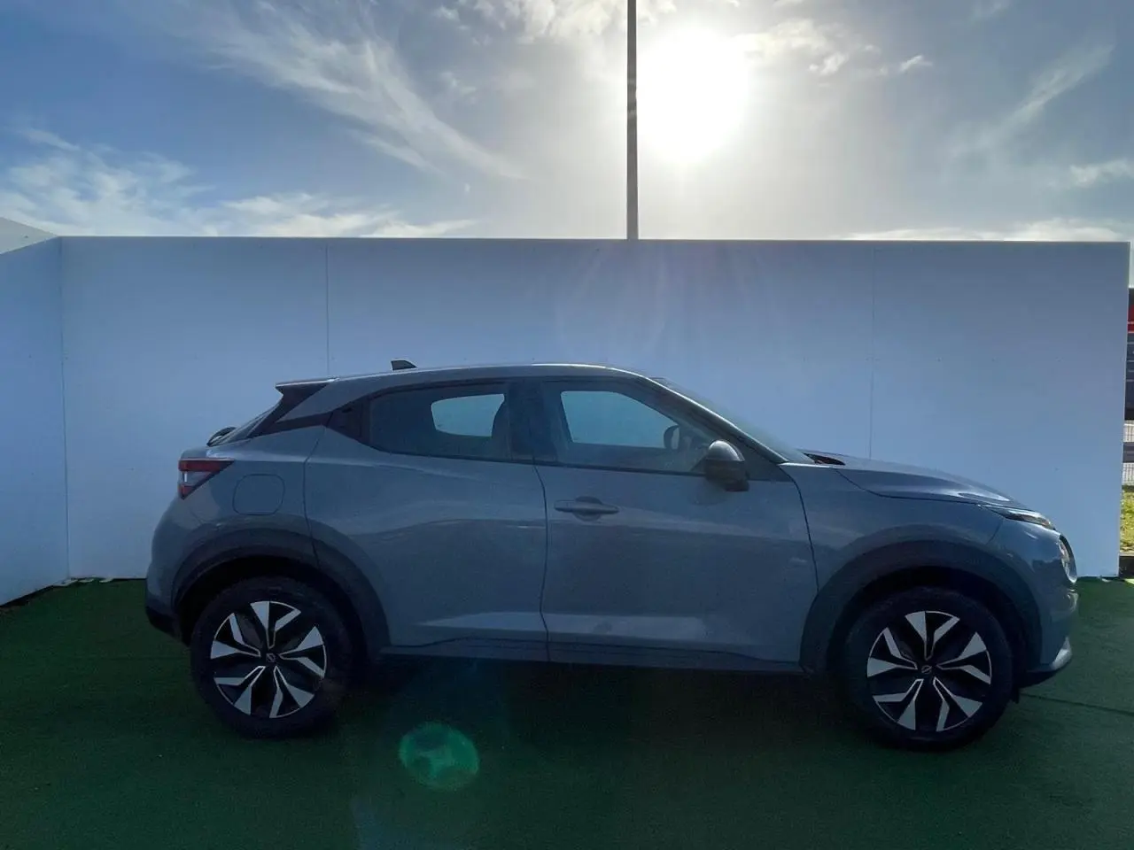 Profil côté gauche du Nissan Juke II 1.0 DIG-T 114 Tekna 2024 en gris ceramic avec jantes alliage noires.