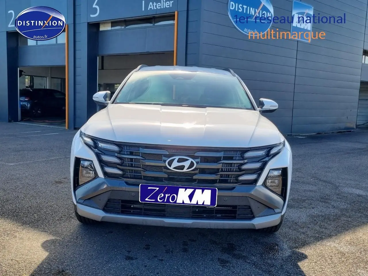 Vue frontale d'un Hyundai Tucson blanc atlas 2025 avec calandre grise et feux LED distinctifs.