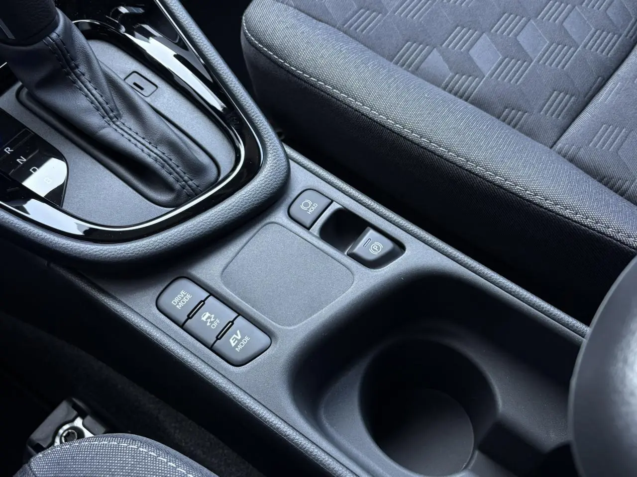 Gros plan sur la console centrale de la Toyota Yaris Hybride 2025, montrant la boîte auto et les commandes de modes de conduite.