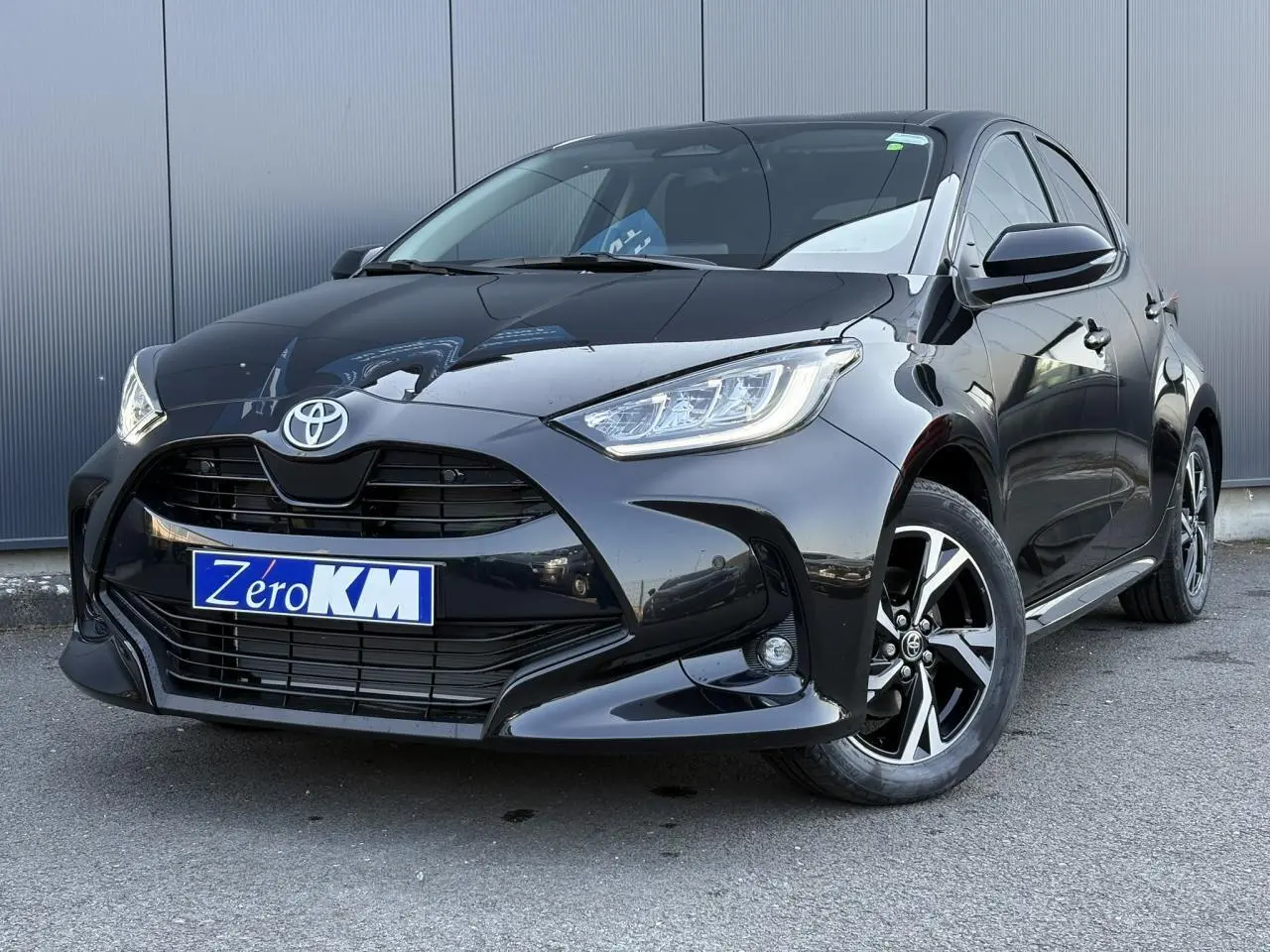 Toyota Yaris Hybride 2025 noir intense vue 3/4 avant droit avec jantes alliage et calandre noire brillante