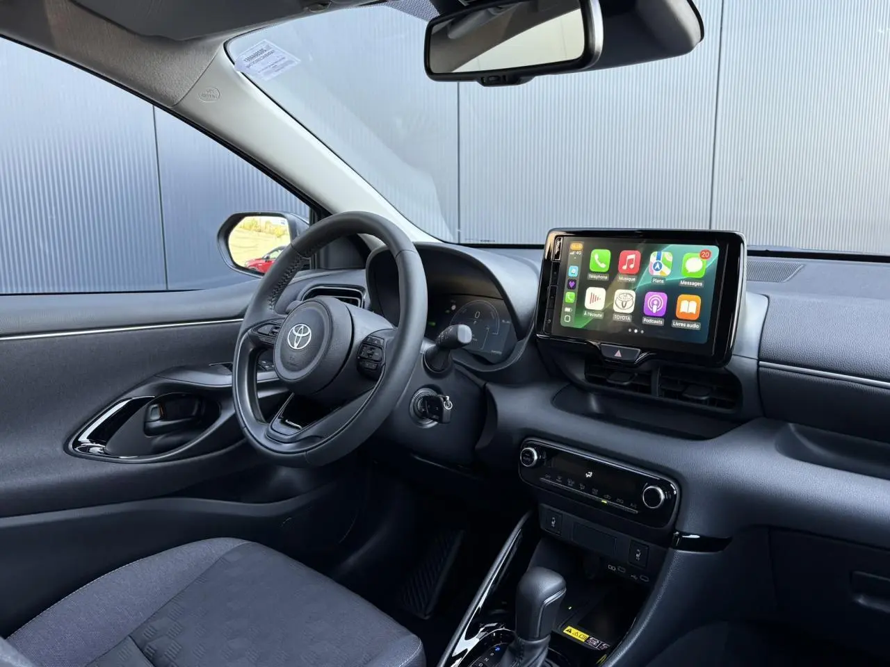 Intérieur de la Toyota Yaris Hybride 2025 vu côté conducteur, avec volant cuir et écran tactile multimédia visible.