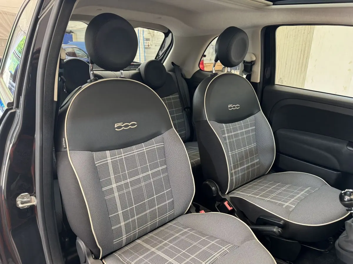 Vue intérieure côté droit montrant les sièges avant noirs avec logo 500 et motif à carreaux gris de la Fiat 500 Lounge 2019.