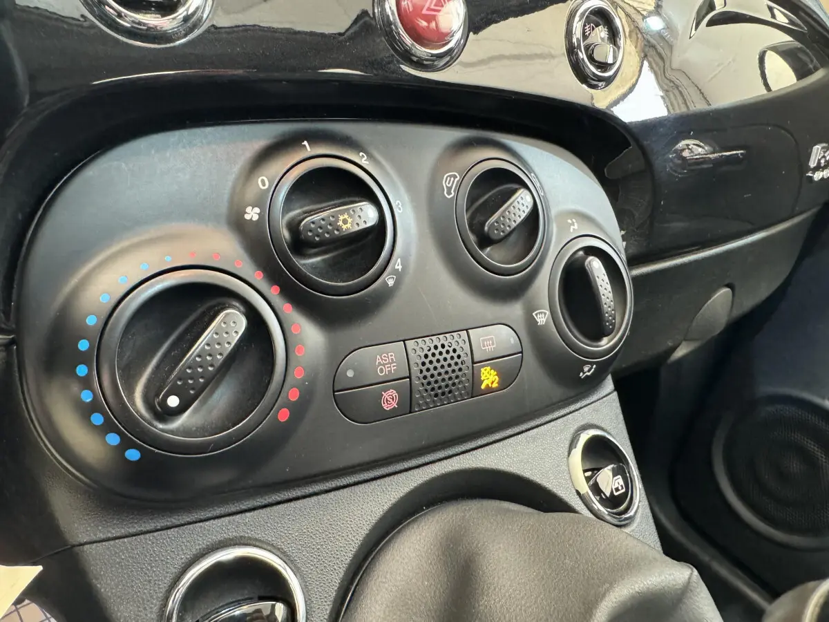 Gros plan sur les commandes de climatisation et tableau de bord noir de la Fiat 500 Lounge 2019.