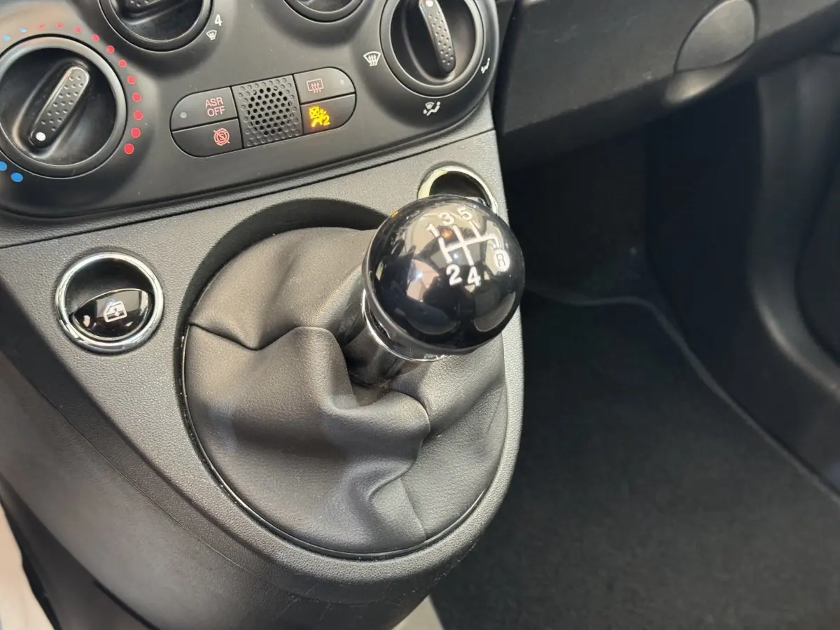 Le levier de vitesses manuel noir de la FIAT 500 1.2 8V 69ch Lounge vu en gros plan dans l'habitacle.