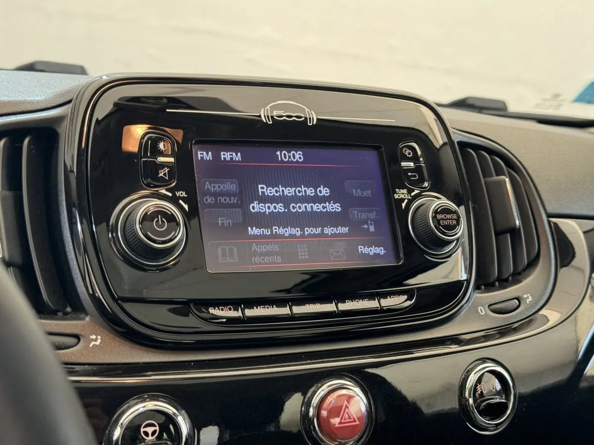 Vue rapprochée du tableau de bord noir brillant de la Fiat 500 2019 avec écran tactile affichant la recherche Bluetooth.