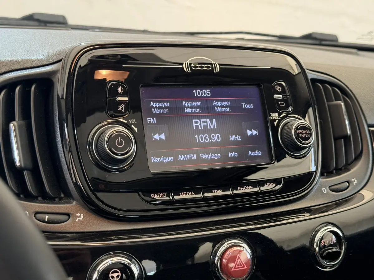 Vue rapprochée du tableau de bord noir de la Fiat 500 Lounge 2019, avec écran tactile affichant la radio FM RFM 103.90 MHz.