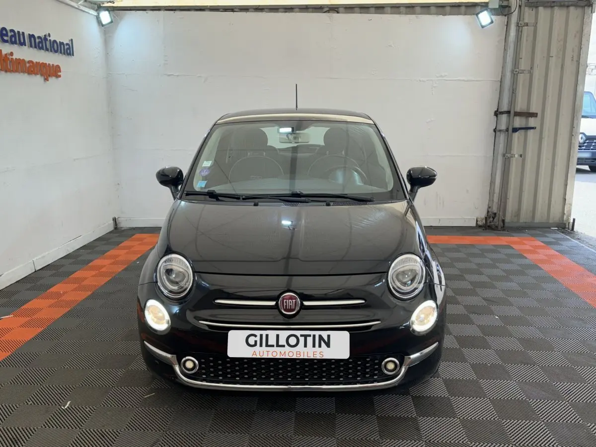 Vue frontale d'une Fiat 500 noire 2019 avec phares allumés et logo Fiat visible sur la calandre.