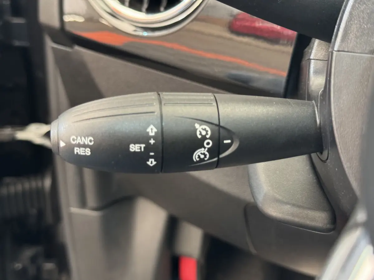 Gros plan sur la commande de régulateur de vitesse noire dans l'habitacle d'une Fiat 500 Lounge 2019.