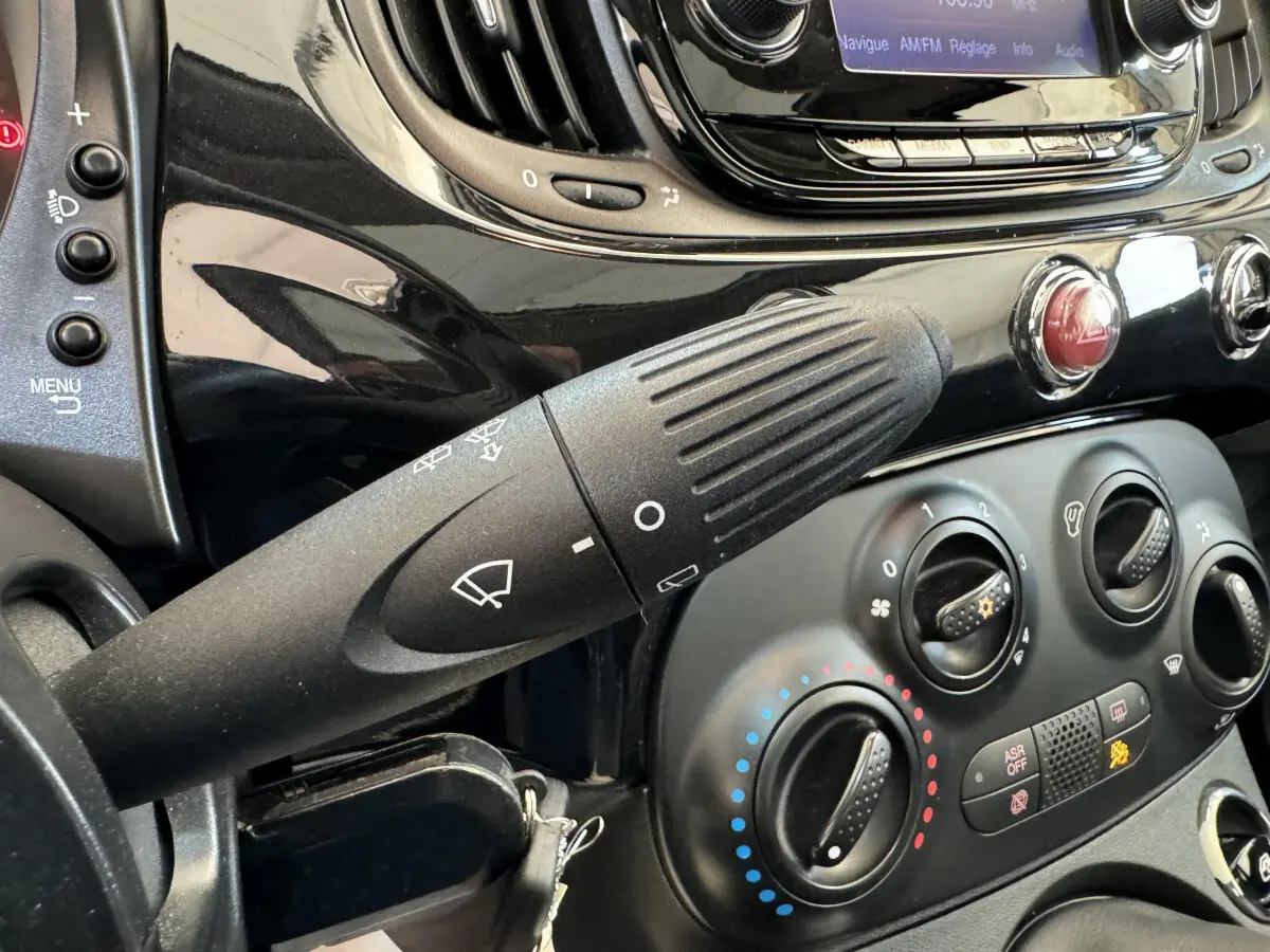 Gros plan sur la commande d'essuie-glace et la console centrale noire d'une Fiat 500 Lounge 2019.