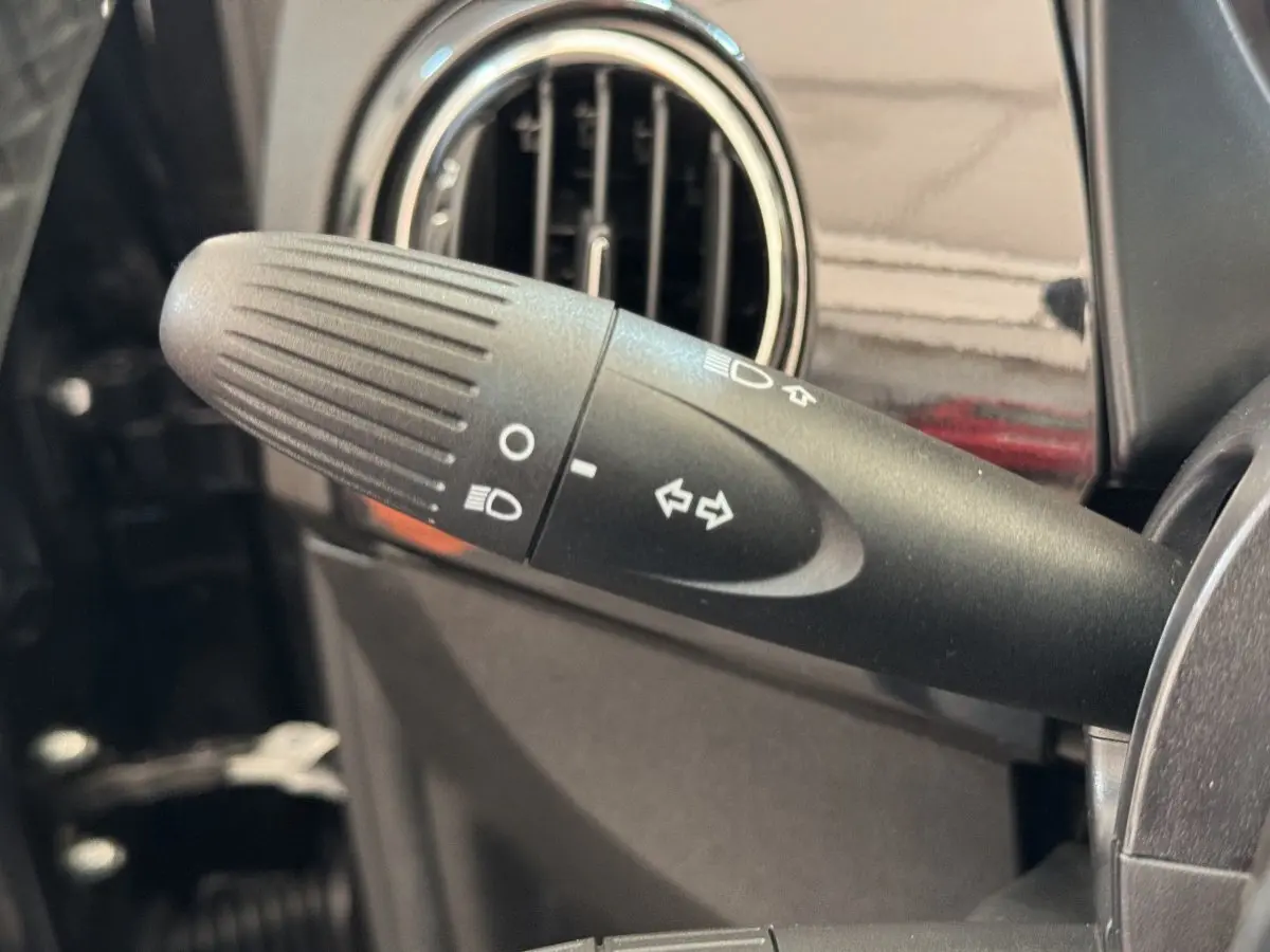 Gros plan sur la commande des clignotants et phares dans l'habitacle noir du Fiat 500 Lounge 2019.