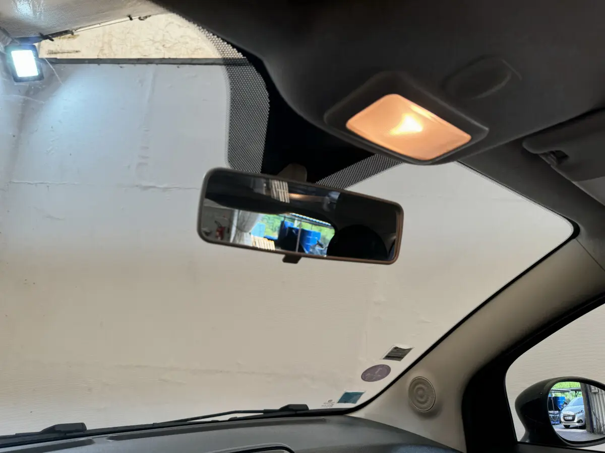 Vue intérieure avant de la Fiat 500 noire, montrant le rétroviseur central et la lumière de plafond allumée.