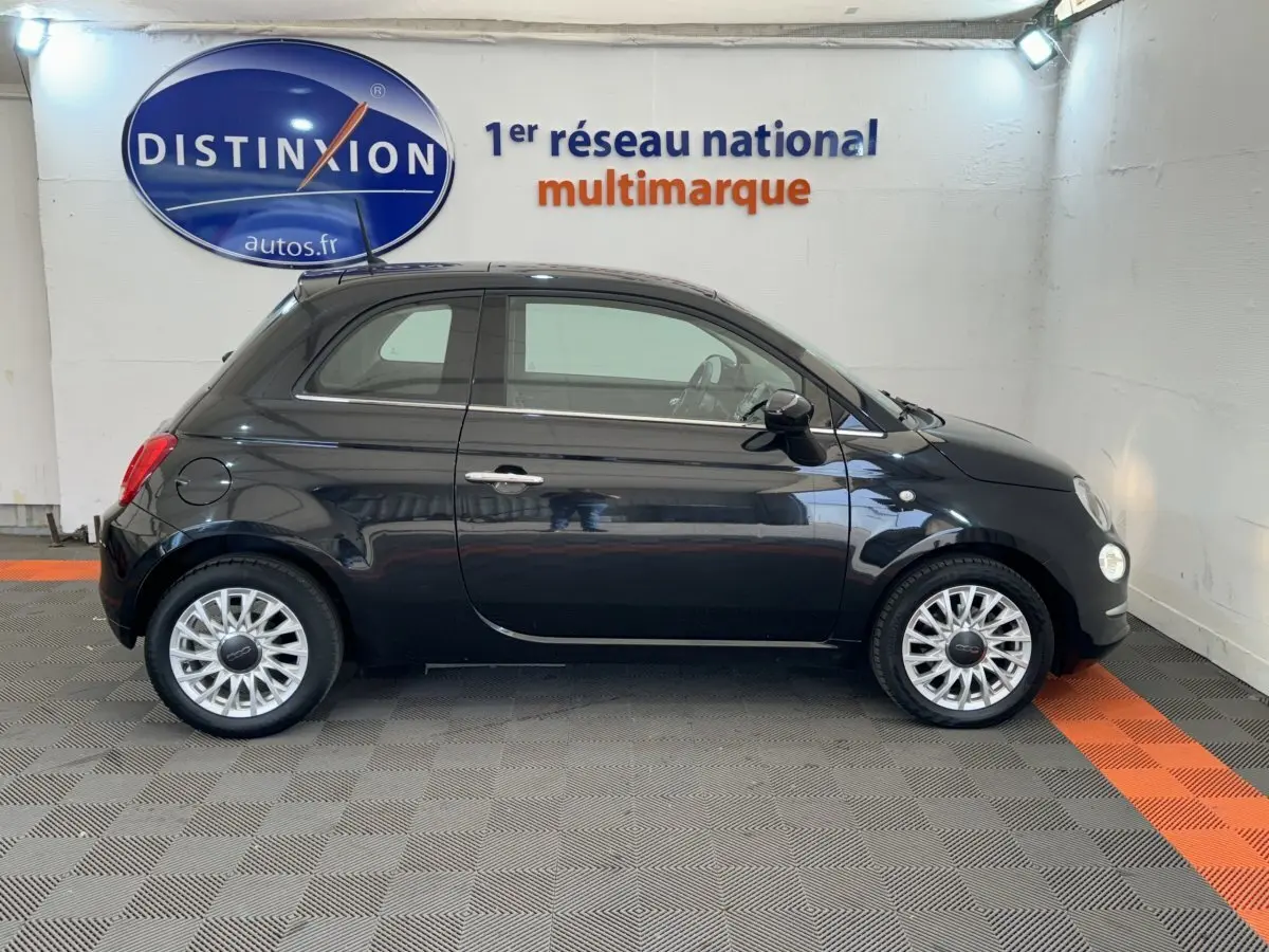 Profil droit d'une Fiat 500 noire 2019 avec jantes alliage et rétroviseurs noirs dans un showroom.
