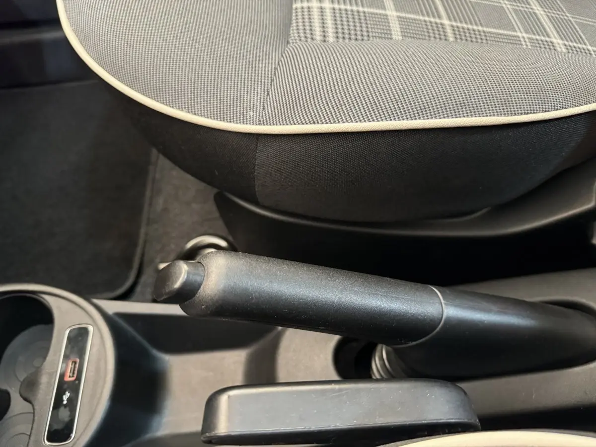 Gros plan sur le frein à main et la console centrale noire avec siège avant gris à motif à carreaux de la Fiat 500 Lounge 2019.
