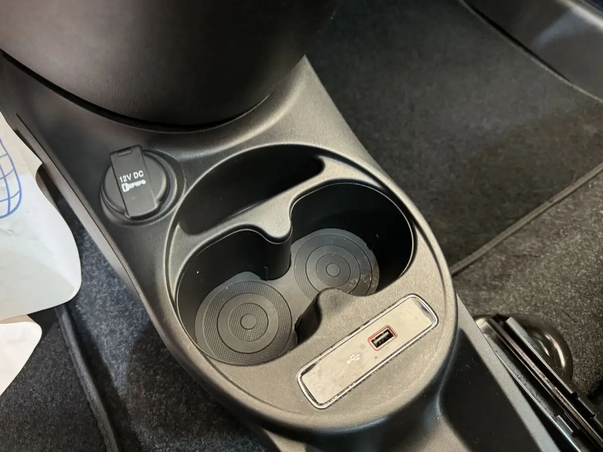 Gros plan sur la console centrale noire de la Fiat 500 Lounge 2019 avec prises USB et 12V et porte-gobelets.