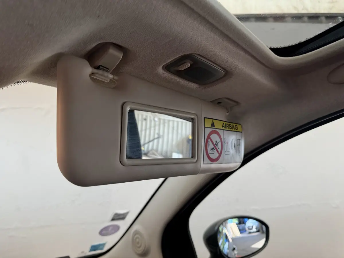Détail du pare-soleil côté conducteur beige avec miroir et avertissement airbag dans un Fiat 500 noir 2019.