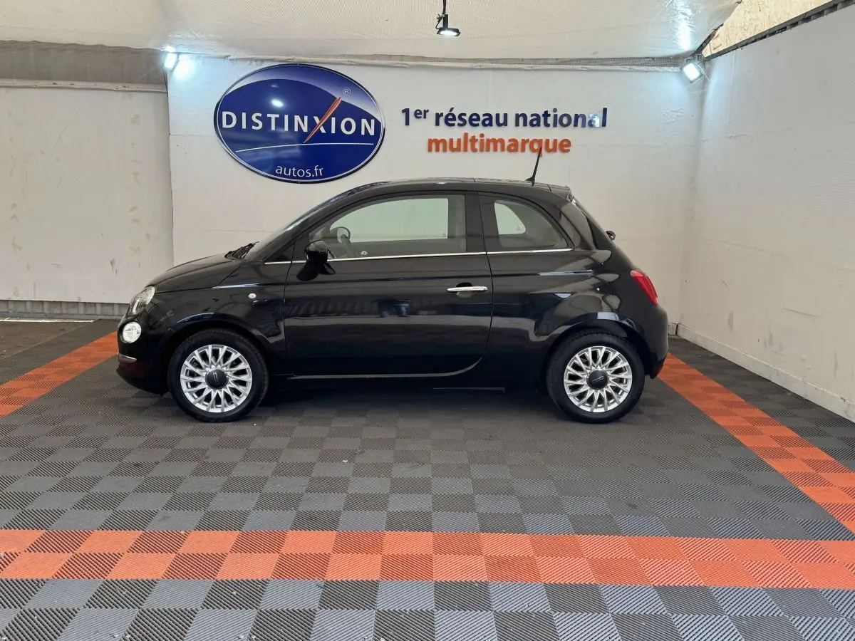 Profil côté gauche d'une FIAT 500 noire 2019 stationnée en intérieur avec jantes argentées et rétroviseurs noirs.