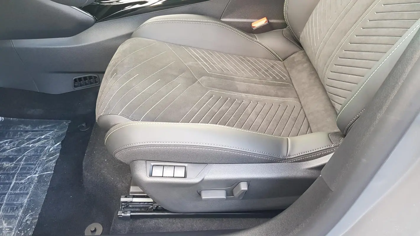Gros plan sur le siège avant droit gris de la Peugeot 208 Hybrid 110 e-DCS6 GT avec réglages électriques visibles.