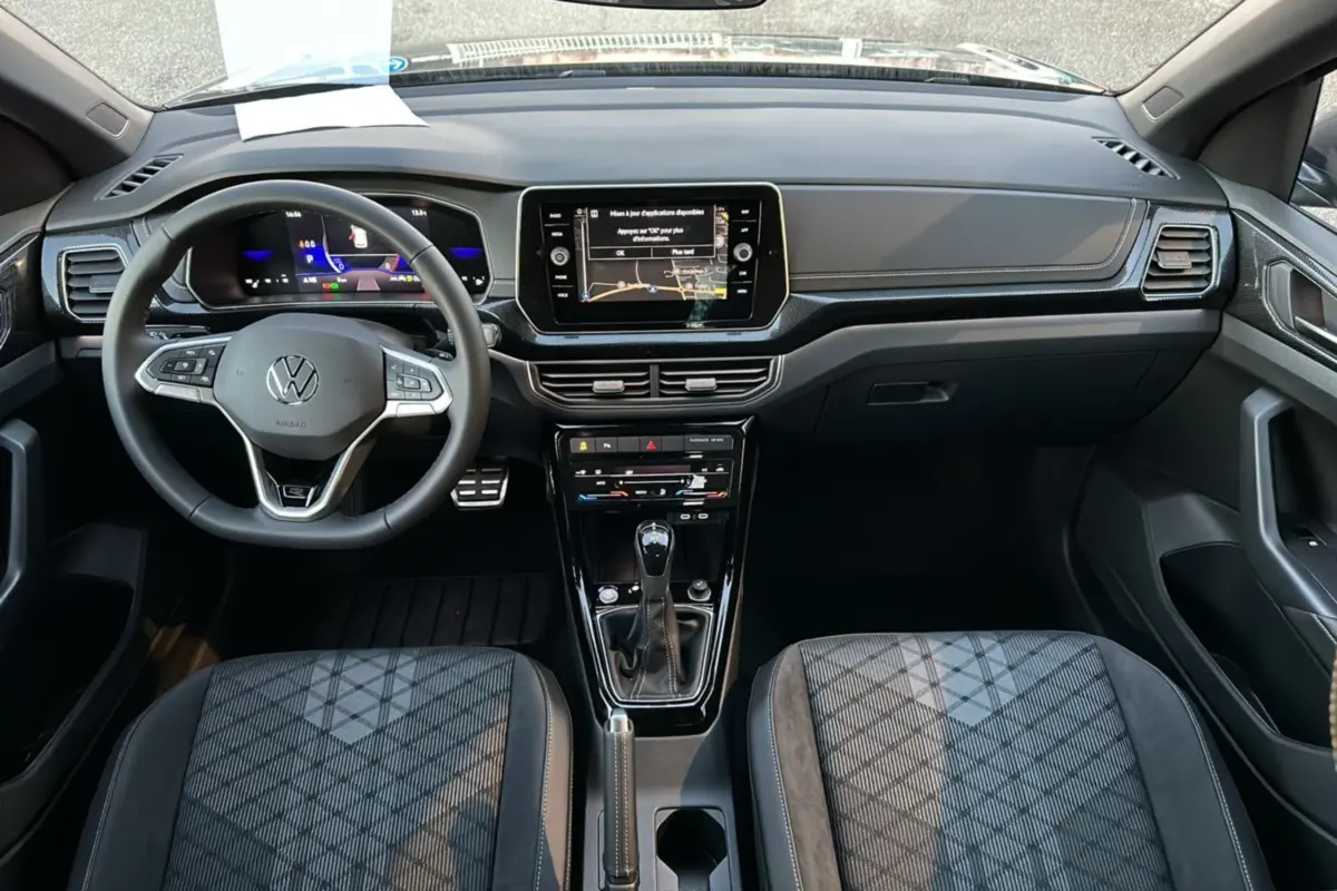 Vue intérieure du tableau de bord et console centrale du Volkswagen T-Cross gris cendré avec volant multifonctions et écran tactile.
