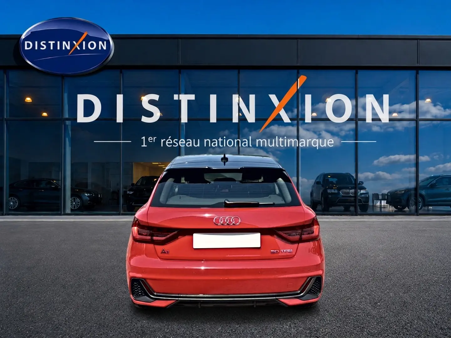 Vue arrière d'une Audi A1 Sportback 30 TFSI rouge et toit noir, avec becquet et feux arrière LED visibles.