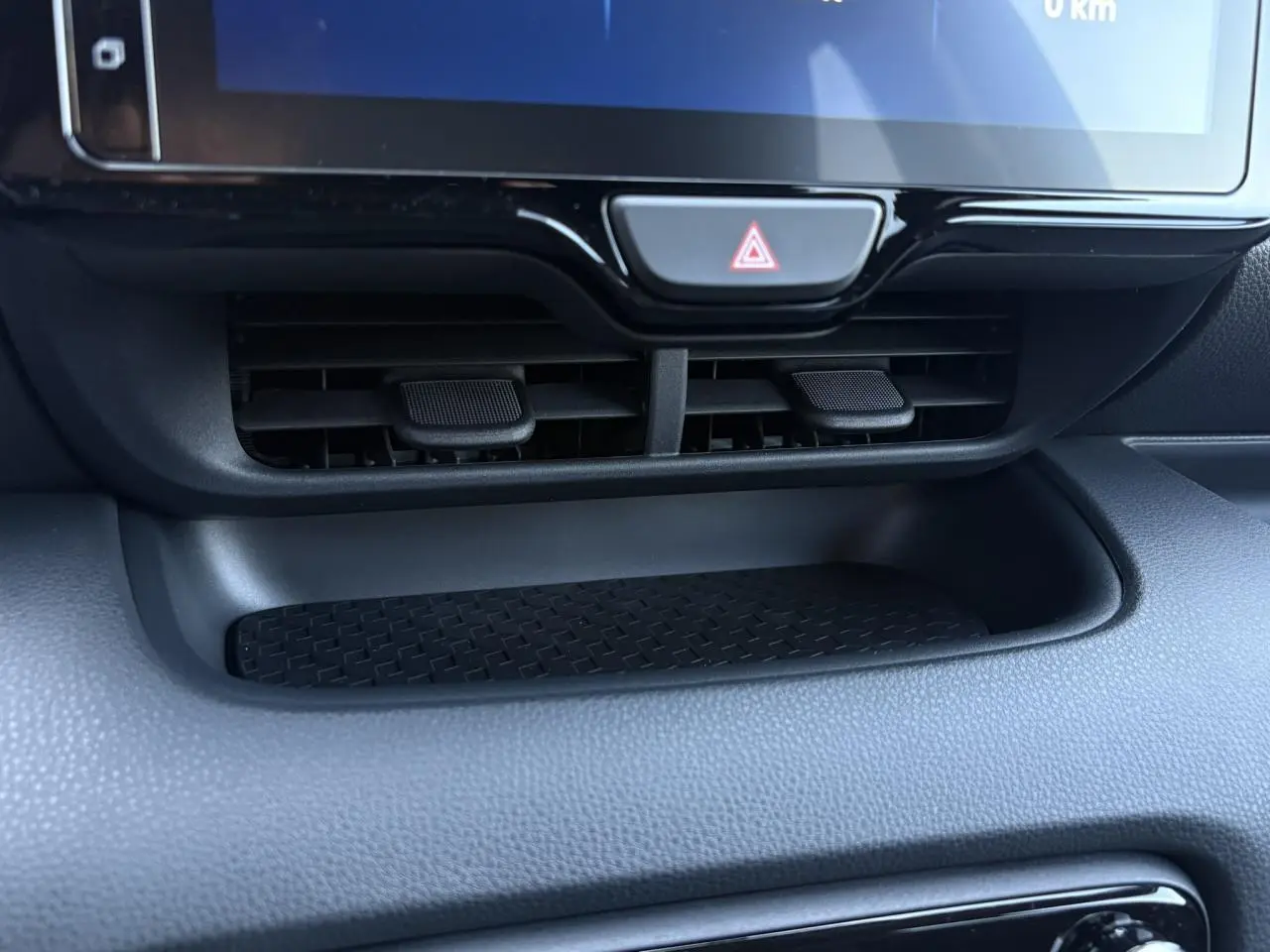 Gros plan sur la console centrale noire de la Toyota Yaris 2025 hybride, montrant les aérateurs et le bouton de warning.
