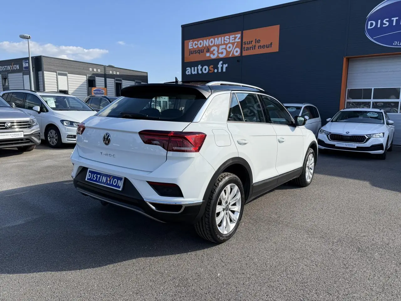 Volkswagen T-Roc blanc vue 3/4 arrière droit avec toit noir et jantes alliage sur parking extérieur.