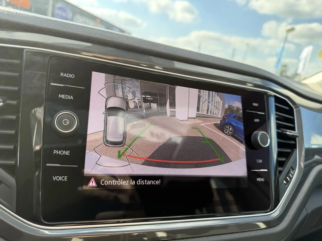 Écran central affichant la caméra de recul du Volkswagen T-Roc 2.0 TDI blanc, vue arrière avec guidage de trajectoire.