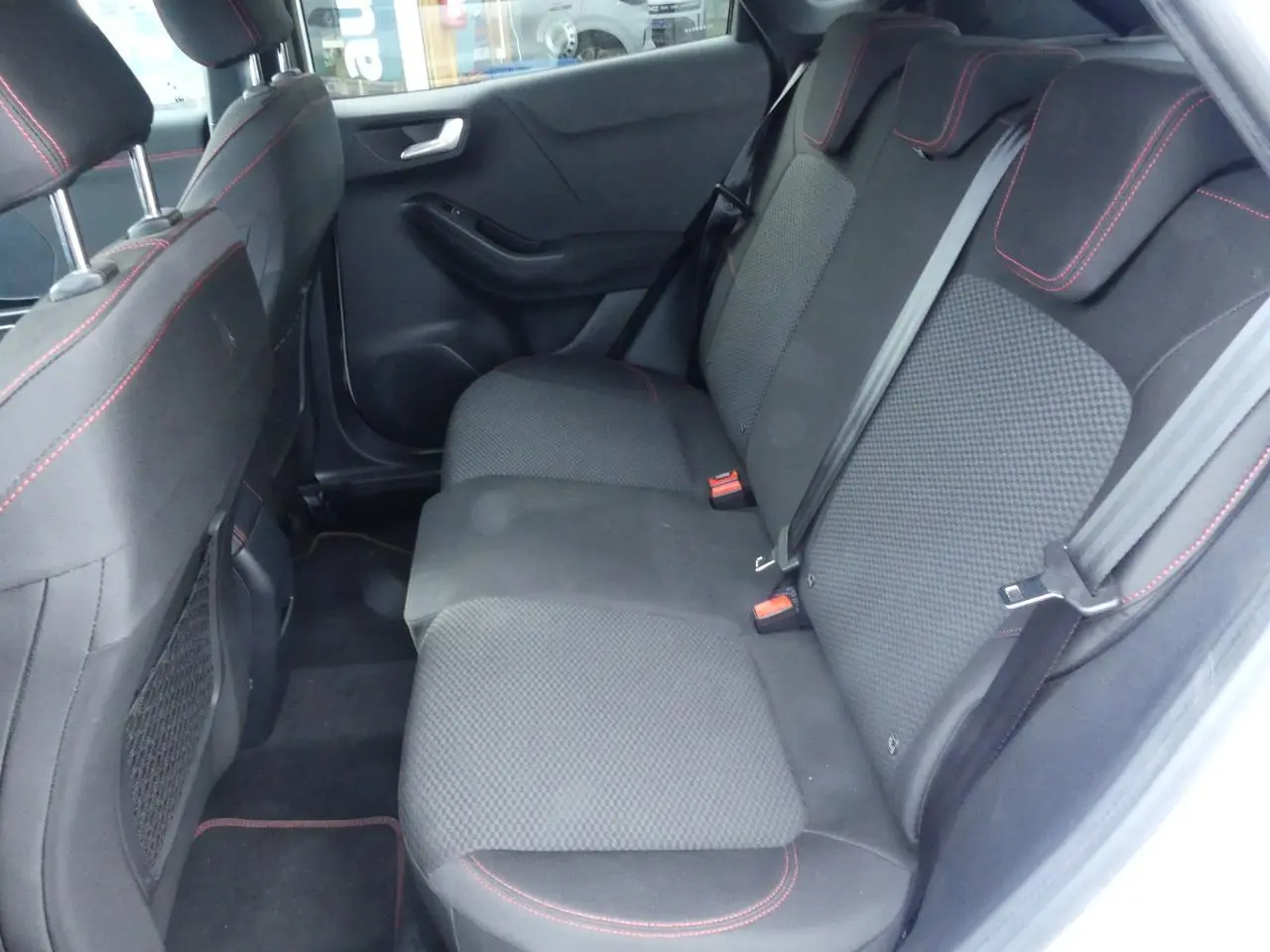 Vue intérieure côté droit sur la banquette arrière noire avec surpiqûres rouges du Ford Puma ST Line blanc 2020.