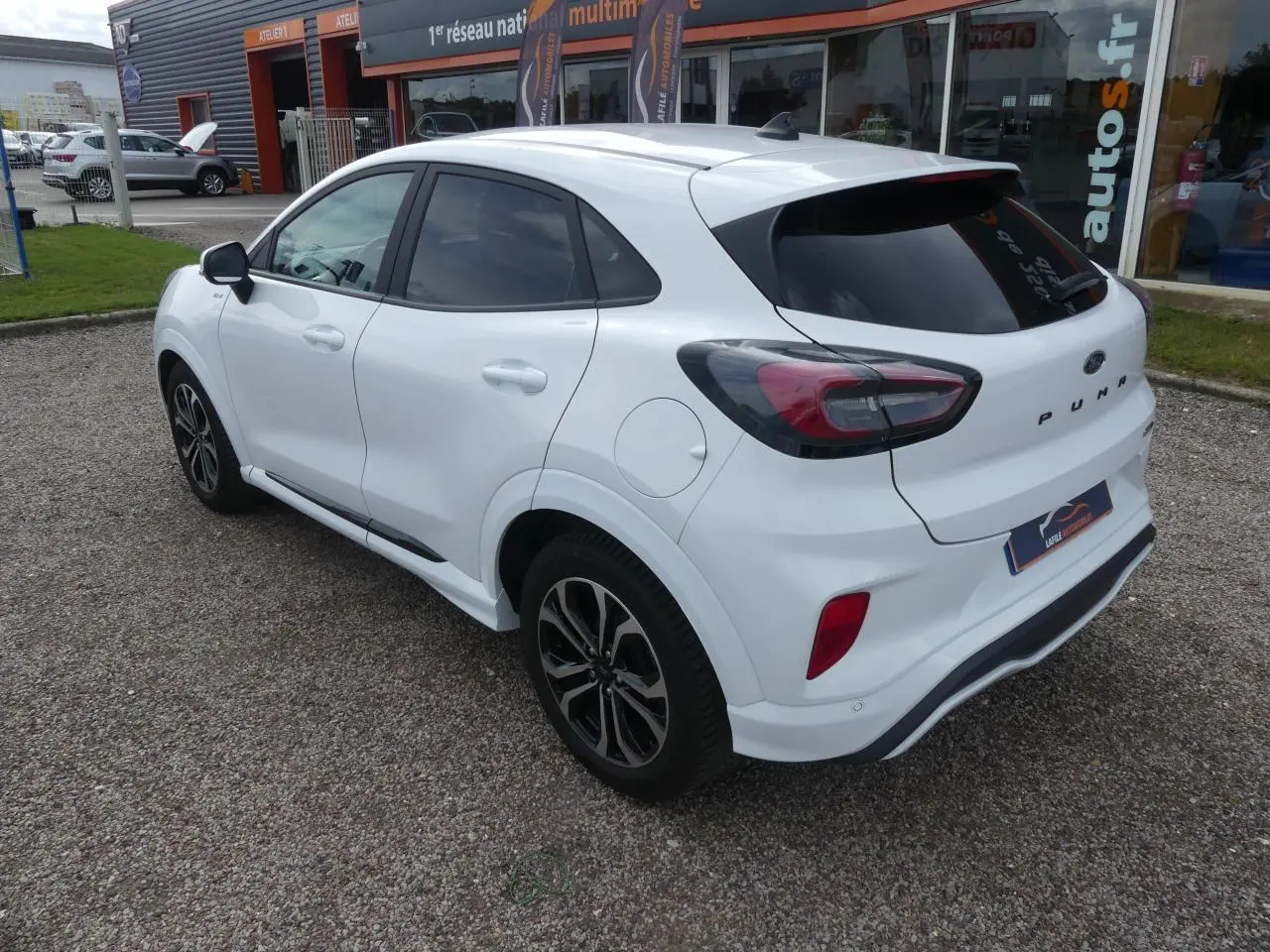 Vue 3/4 arrière droite du Ford Puma blanc ST Line avec vitres arrière surteintées et jantes alliage noires.