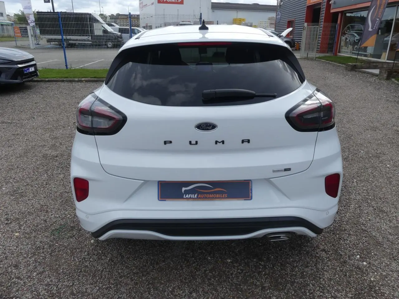 Vue arrière d'une Ford Puma blanche ST Line avec vitres arrière surteintées et sortie d'échappement chromée visible.