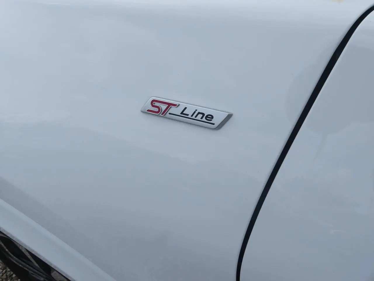 Gros plan sur l'écusson ST Line rouge et noir sur la porte blanche d'une Ford Puma 2020.