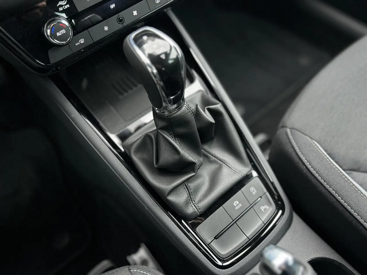 Vue rapprochée de la console centrale du Skoda Kamiq 2025, avec levier de vitesse automatique et accoudoir tissu gris.