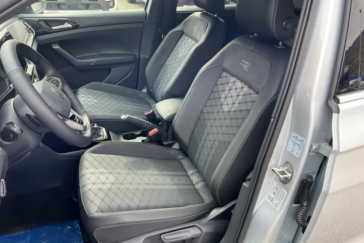 Intérieur avant droit du Volkswagen T-Cross gris argent, sièges tissu avec surpiqûres et logo R sur appuie-tête.