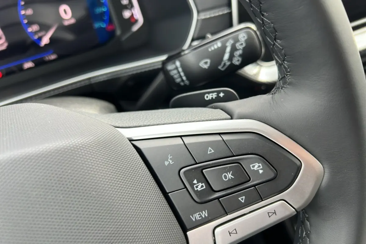 Gros plan sur le volant cuir multifonctions côté gauche du Volkswagen T-Cross gris argent avec commandes intégrées.