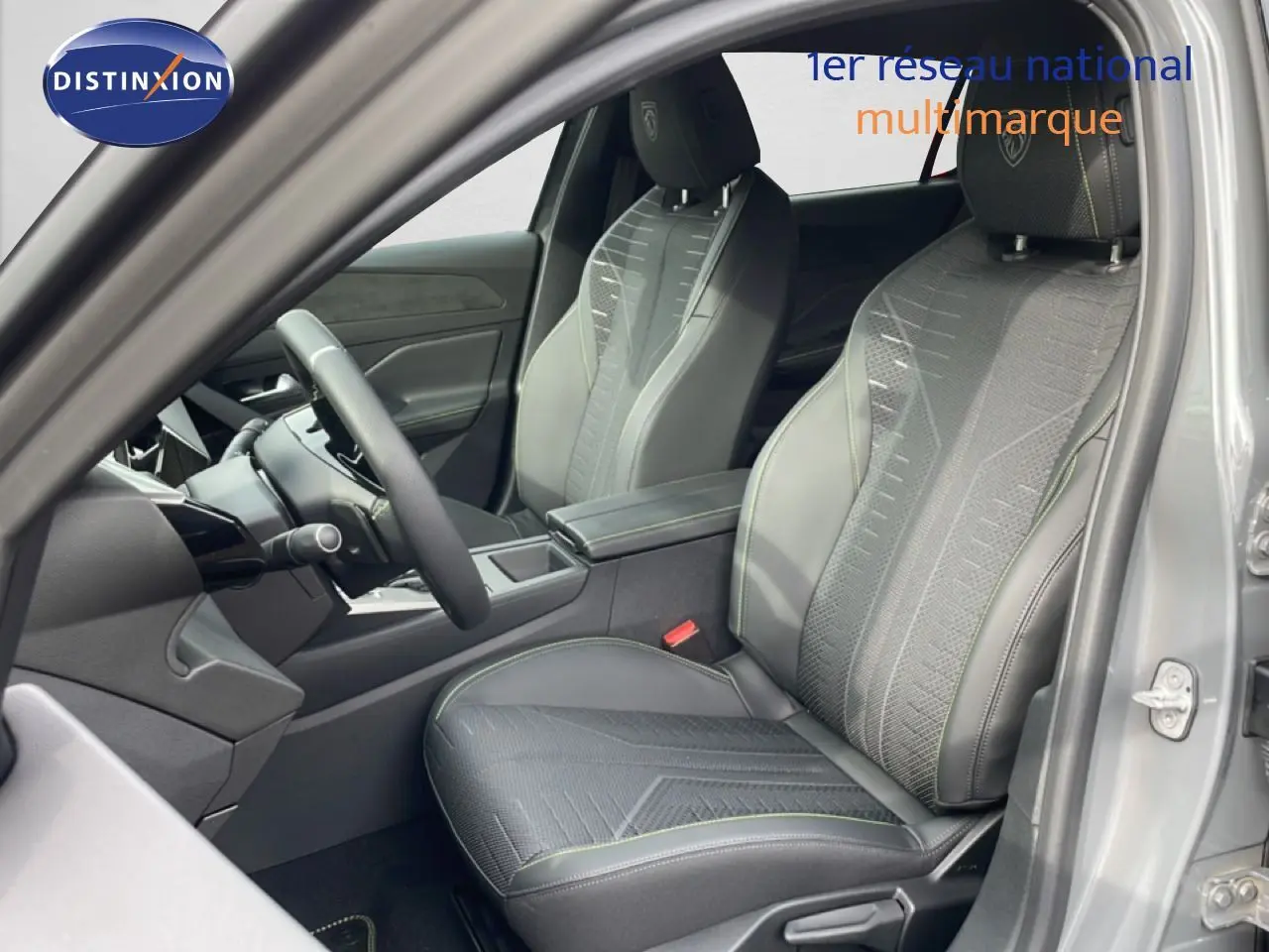 Vue intérieure côté conducteur de la Peugeot 308 gris selenium, mettant en valeur les sièges en tissu et cuir avec surpiqûres vertes.